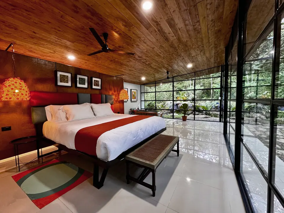 Riverside suite bedroom with glass walls opening to the garden