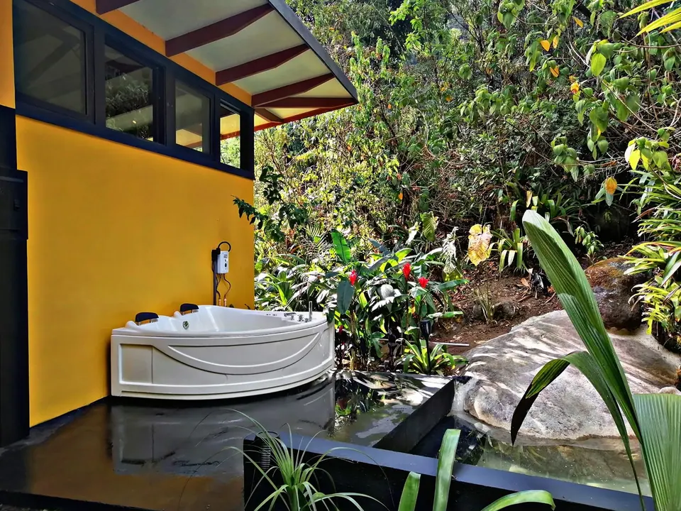 Private outdoor jacuzzi beside a yellow casita in the rainforest