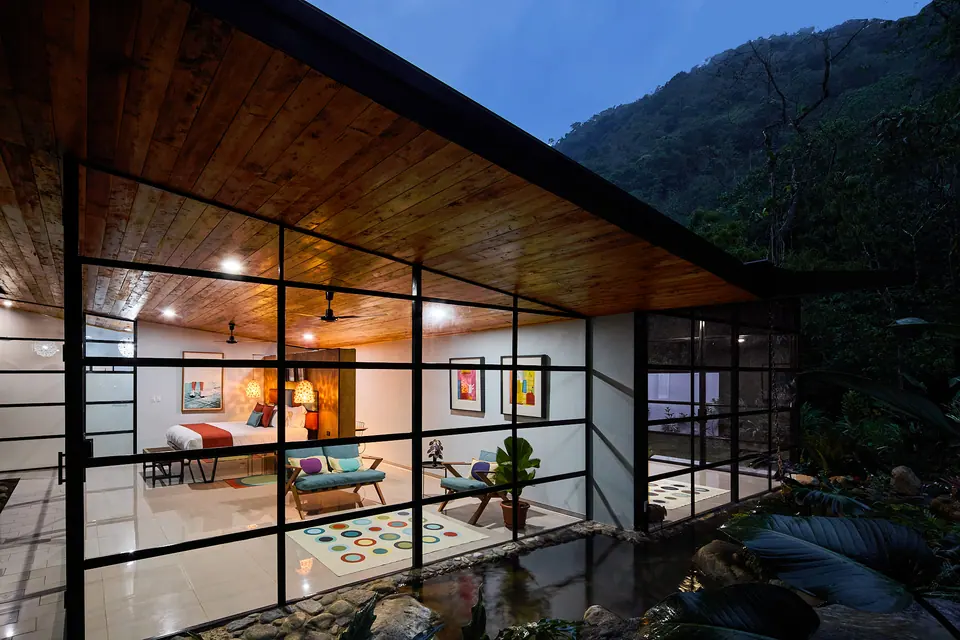 Glass-walled suites glowing at dusk in the rainforest